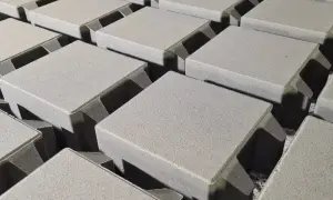 Szare, kwadratowe kostki brukowe ułożone w rzędach, gotowe do stworzenia trwałej nawierzchni. Różne rodzaje kostki brukowej oferują wiele możliwości aranżacji.