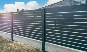 Nowoczesne ogrodzenie z poziomych desek na betonowej podmurówce.