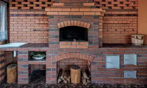 Murowany grill z cegły z paleniskiem, miejscem na drewno i umywalką.