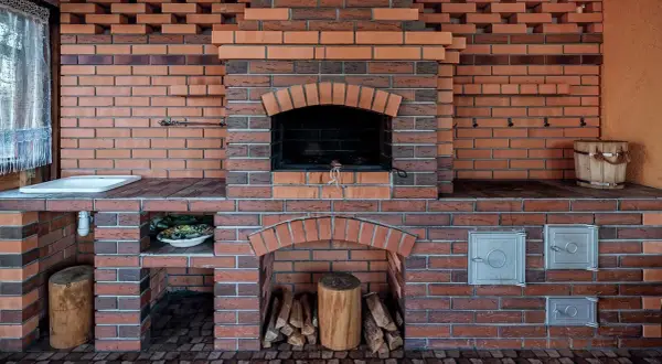Murowany grill z cegły z paleniskiem, miejscem na drewno i umywalką.