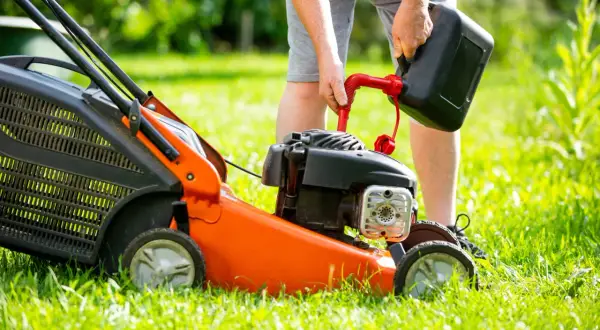 Mężczyzna nalewa paliwo do kosiarki. Zastanawiasz się, jakie paliwo do kosiarki będzie najlepsze?