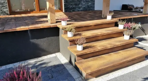 Drewniane schody tarasowe z doniczkami wrzosów.