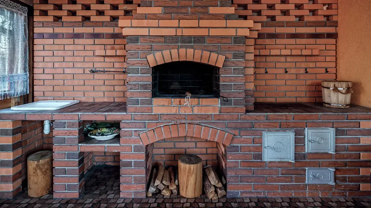 Murowany grill z cegły z paleniskiem, miejscem na drewno i umywalką.