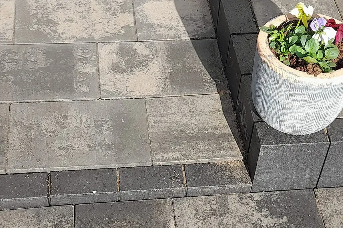 Różne rodzaje kostki brukowej tworzą nowoczesną nawierzchnię. Na pierwszym planie ciemniejsza kostka, dalej jaśniejsza z kamiennym wzorem.