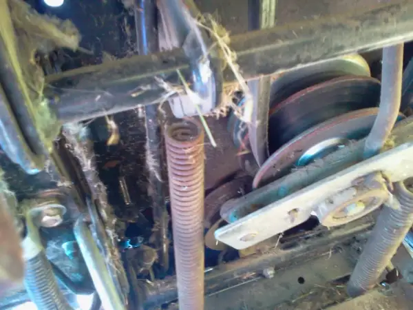 Mechanizm kosiarki traktorka MTD z widocznym pasem, sprężyną i kołami pasowymi. Pomoc w zrozumieniu, jak założyć pasek do kosiarki traktorka MTD.